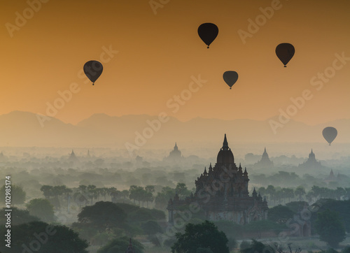 The silhouette of ancient pagodas in the mist during sunrise wit