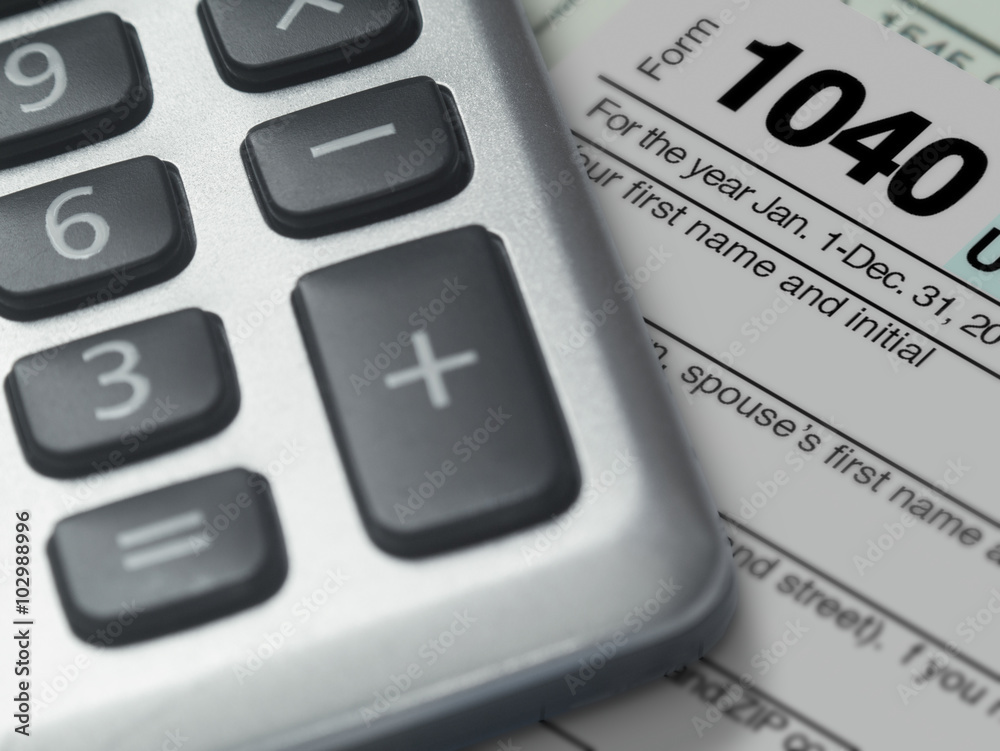 Photograph of a calculator and IRS 1040 form in close up. Photograph of a calculator and IRS 1040 form in close up.
