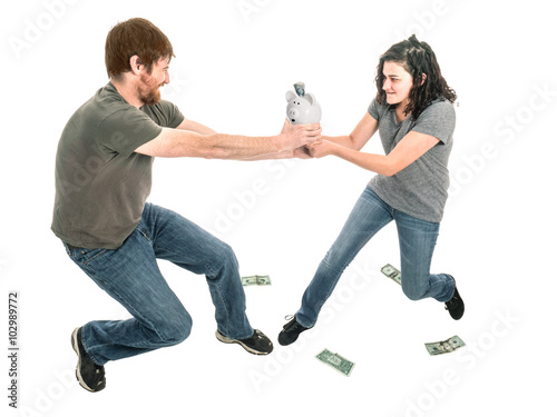 Photograph of a young heterosexual couple engaged in a tug-of-war over control of the piggy bank.