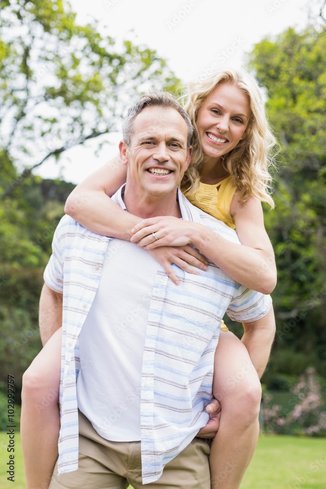 Obraz premium Happy husband giving piggy back to his wife