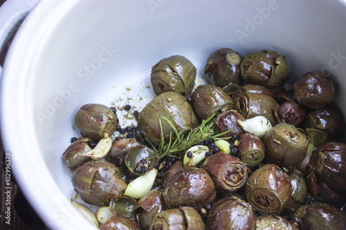 Artischockenherzen mit Knoblauch, Rosmarin und Olivenöl mariniert in einer weien Schüssel photo