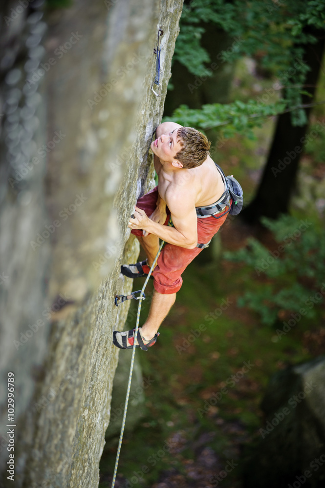 Young athletic man climbing on cliff wall with rope engaged Young athletic man climbing on cliff wall with rope engaged