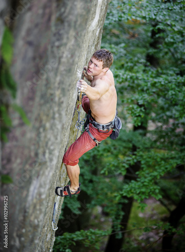  rock climber climbs on overhanging cliff in summer time