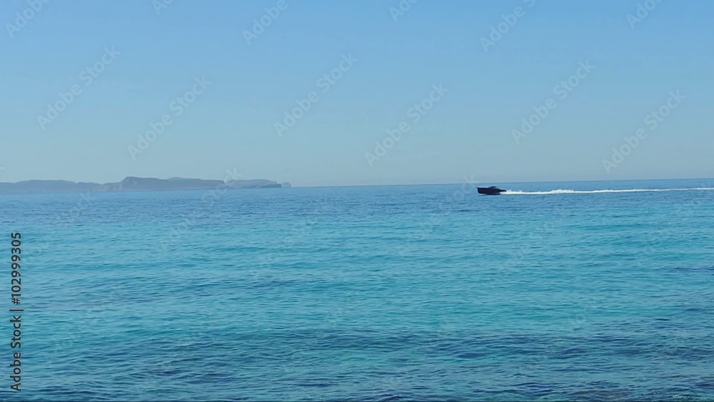 Seascape. Bright sunny day. Turquoise sea, dark boat coming from the distance Seascape. Bright sunny day. Turquoise sea, dark boat coming from the distance