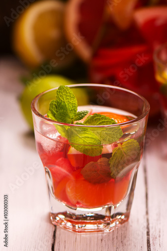 Glass of summer drink with citrus fruits, ice and mint. Selective focus