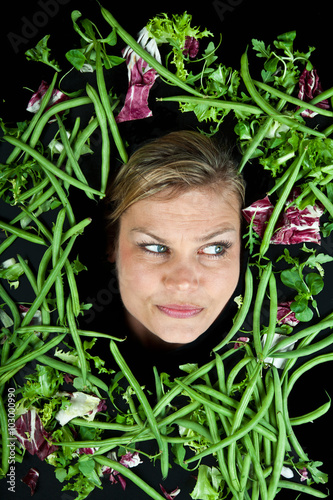 Cute blond girl shot in studio with vegetables aroound the head photo