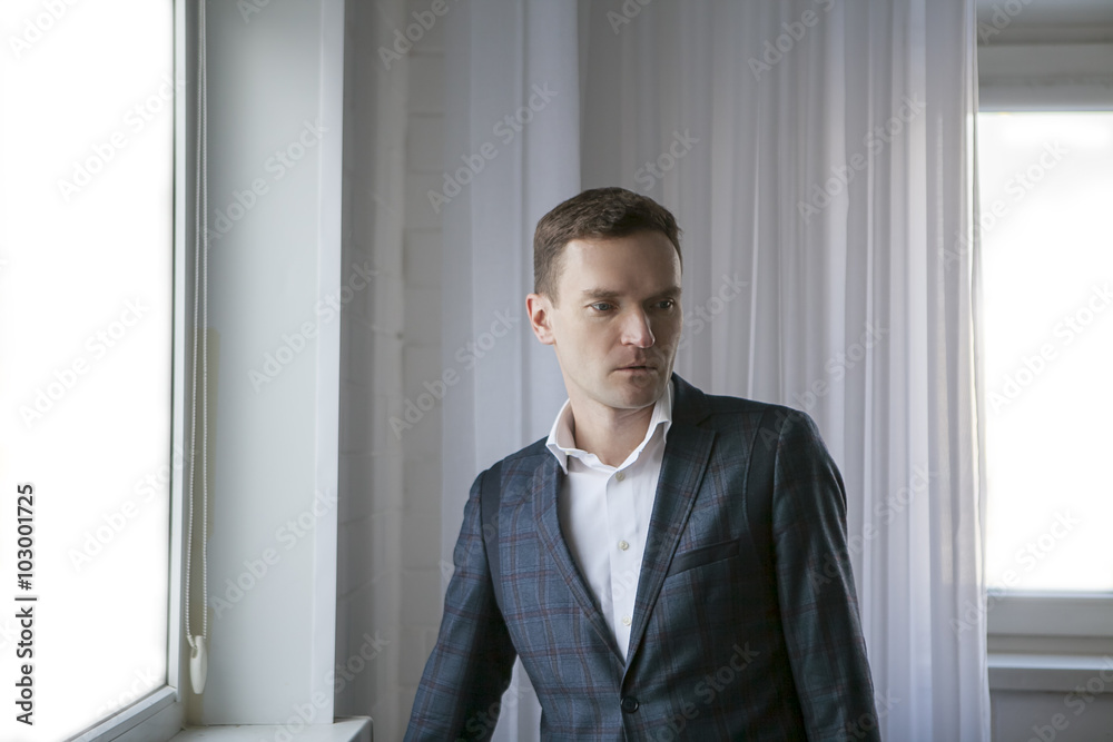 businessman standing thoughtfully in an empty room with white windows and a curtain concept of loss being lost businessman standing thoughtfully in an empty room with white windows and a curtain concept of loss being lost