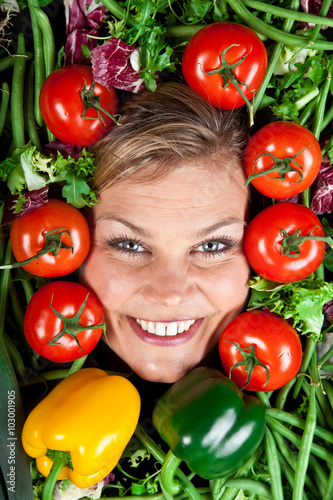 Cute blond girl shot in studio with vegetables aroound the head photo