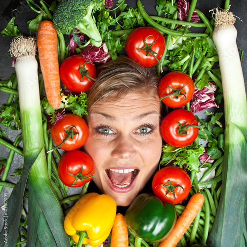 Cute blond girl shot in studio with vegetables aroound the head photo