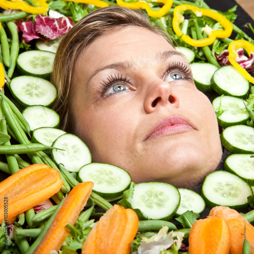 Cute blond girl shot in studio with vegetables aroound the head photo