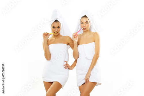 Two girls brush their teeth after shower