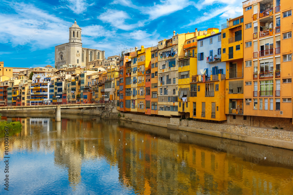 Colorful yellow, red and orange houses with the Catalan flag reflected in water river Onyar, in Girona, Catalonia, Spain. Saint Mary Cathedral at background.