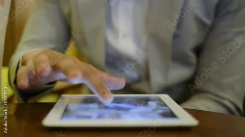 Locked-on shot of a businessman sitting in a café and using a digital tablet photo
