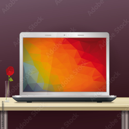 Laptop with polygonal screen background on office desktop