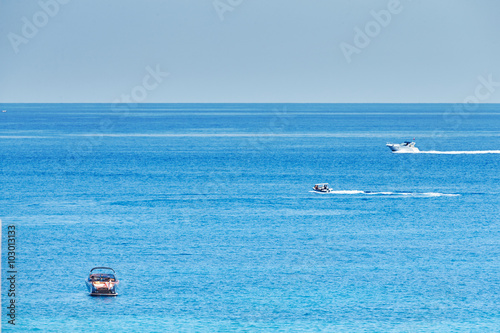 Motorboat Riva is anchored in the sea near the beach Menton, couple sunbathing