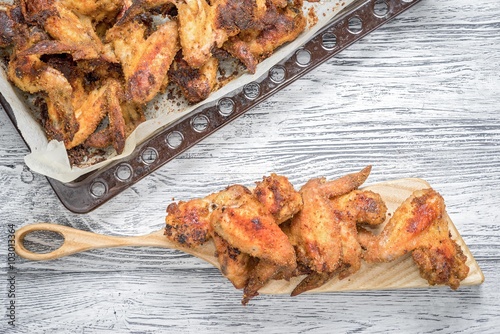 roasted spicy chicken wings on tray and cutting board with copy space