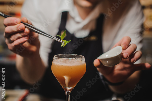 Barman is decorating cocktail with rocket