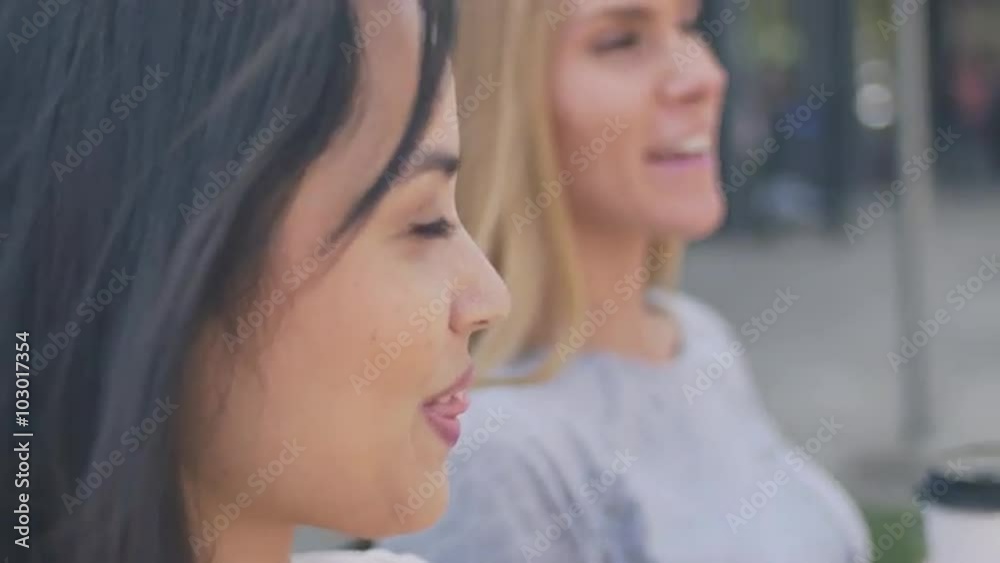 Close up of two friends sitting on a bench and talking Close up of two friends sitting on a bench and talking
