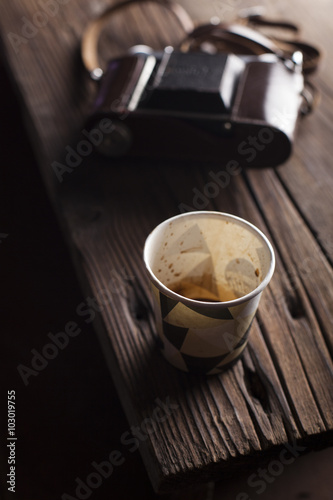 Empty coffee cup with camera in background kept on table photo