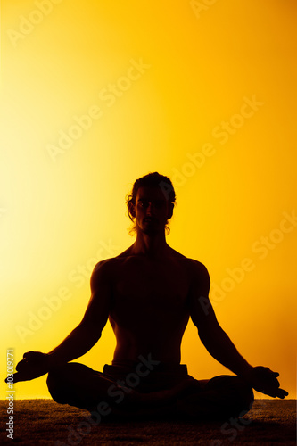 The man practicing yoga in the sunset light