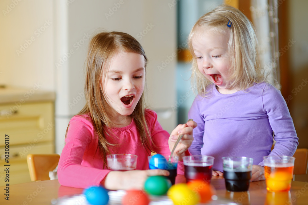 Two little sisters painting colorful Easter eggs Two little sisters painting colorful Easter eggs