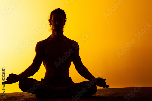 The man practicing yoga in the sunset light