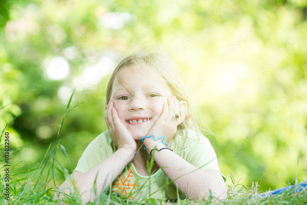 Happy little girl laying on the grass in the park Happy little girl laying on the grass in the park
