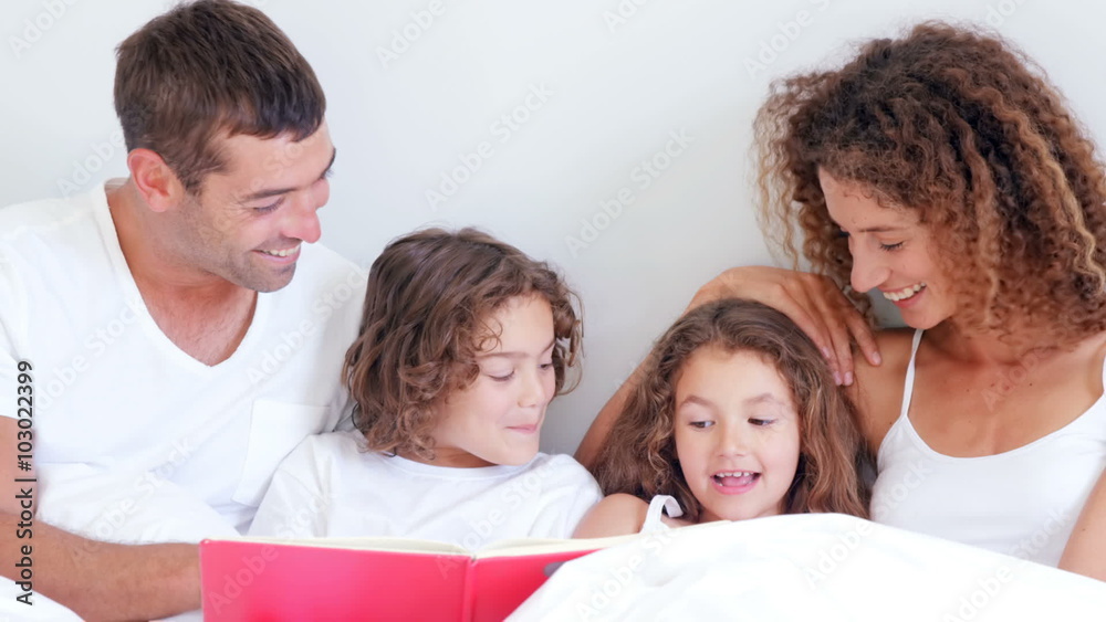 Focused parents reading tale to their children Focused parents reading tale to their children