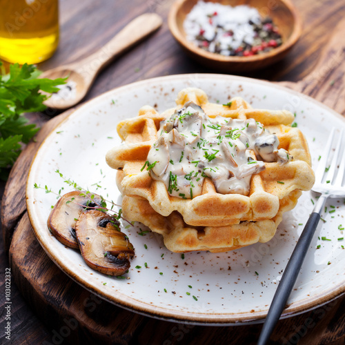 Savory waffles with corn and mushroom creamy sauce on a wooden background