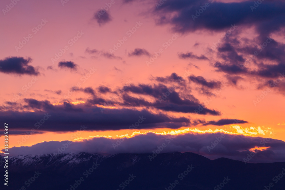 Majestic vivid sunset/sunrise with clouds over mountain rage