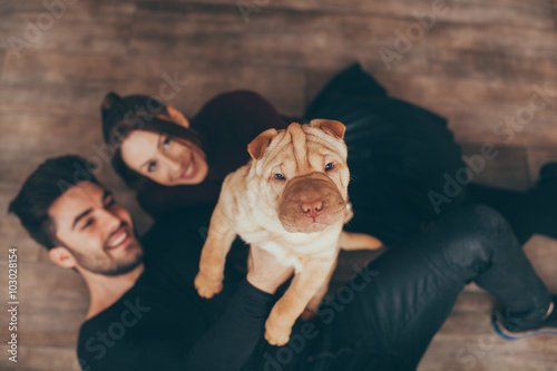 Happy couple holding Shar Pei puppy photo