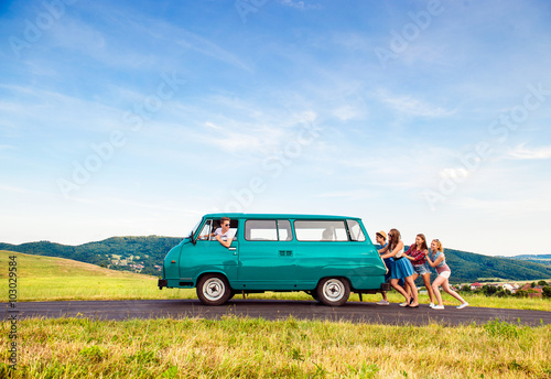 Jumping frieds with campervan, green nature and blue sky