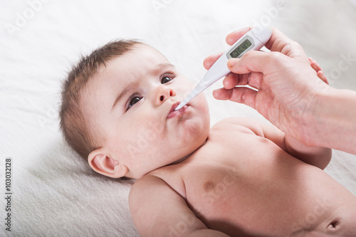Doctor measures the temperature of little baby.