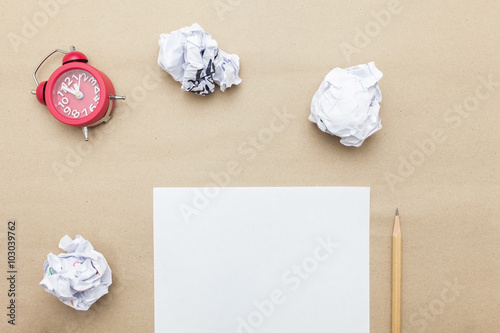 Business concept:red clock,white blank paper,crumpled paper and color pencil,pencil,pen on brown paper background