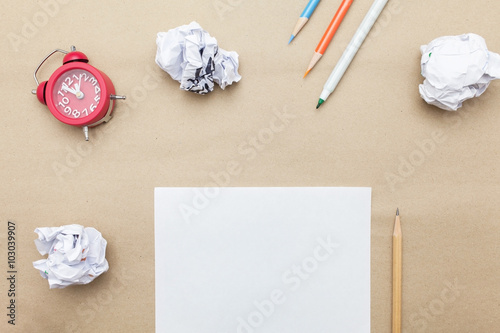 Business concept:red clock,white blank paper,crumpled paper and color pencil,pencil,pen on brown paper background