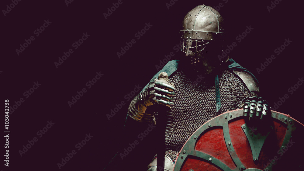 Naklejka premium Średniowieczny rycerz w zbroi z mieczem i tarczą.