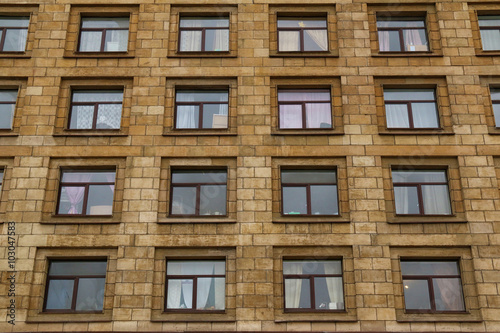 Many windows in row on facade of urban apartment building front view