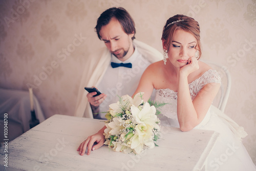 the groom is distracted by the phone during a wedding photosession