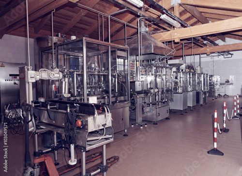 Wine bottling equipment line in a hangar, toned