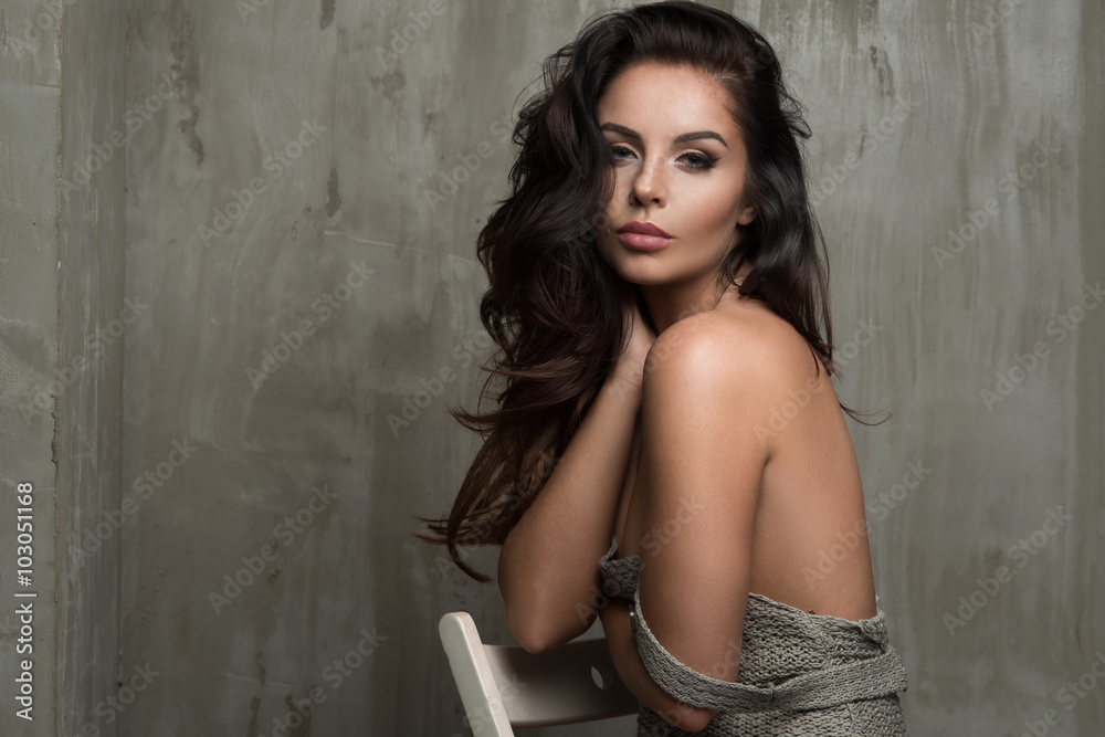 Fototapeta premium Sensual brunette woman with sitting on chair, looking at camera.