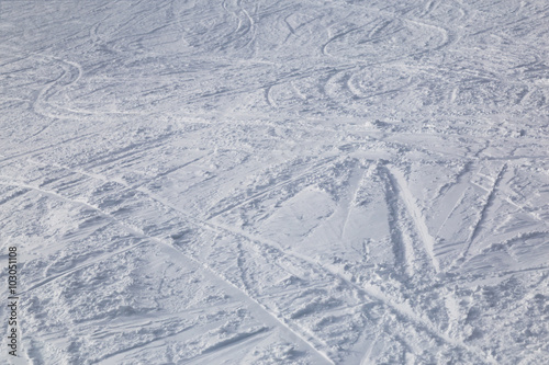 Traces from skiing on white snow .