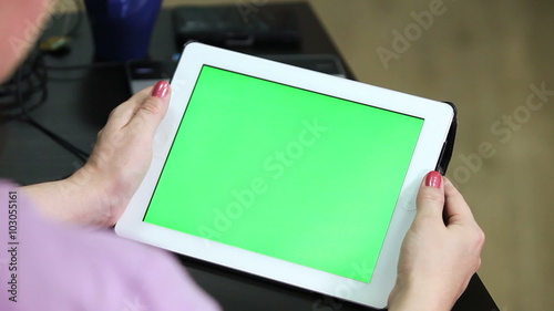 Unrecognizable Caucasian woman holding tablet in hands with green screen chromakey