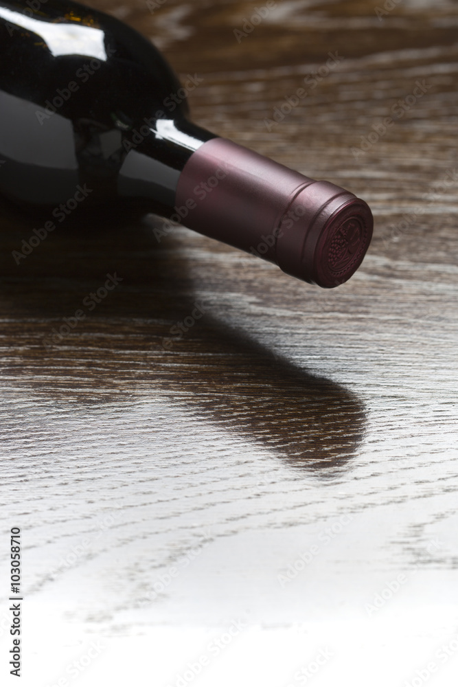 Red Wine Bottle Laying on Wood Fading Down to White