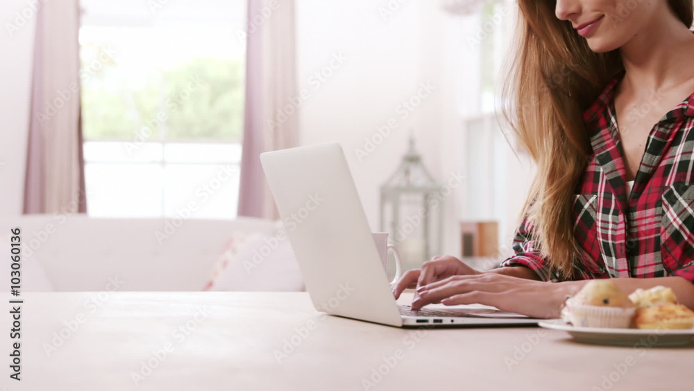 Pretty woman using laptop with muffins Pretty woman using laptop with muffins