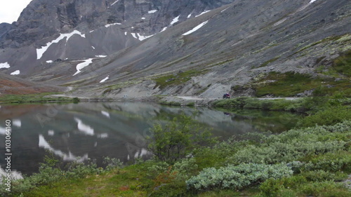 Quad bike driving on the mountain road near tranquil beautiful lake with reflection. Khibiny massif, Kolsky peninsula, Russia photo