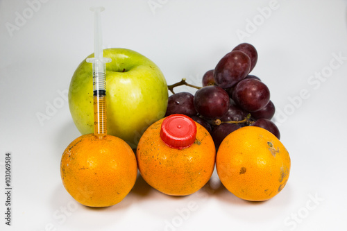 A real orange fruit was sucked with syringe with other fruit surrounded