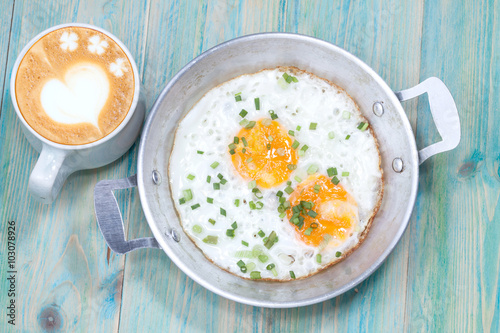 Hot late art coffee and Egg in pan on wood table
