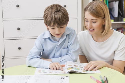 teacher reads a textbook with a boy, elementary school student