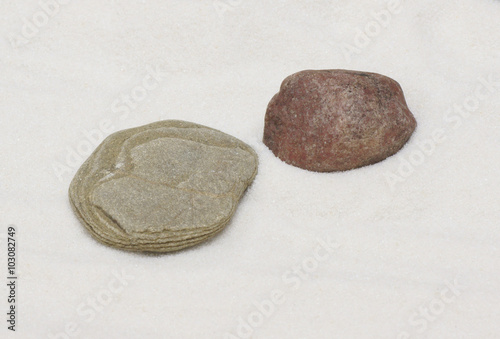 Two stones lie on the white sand.