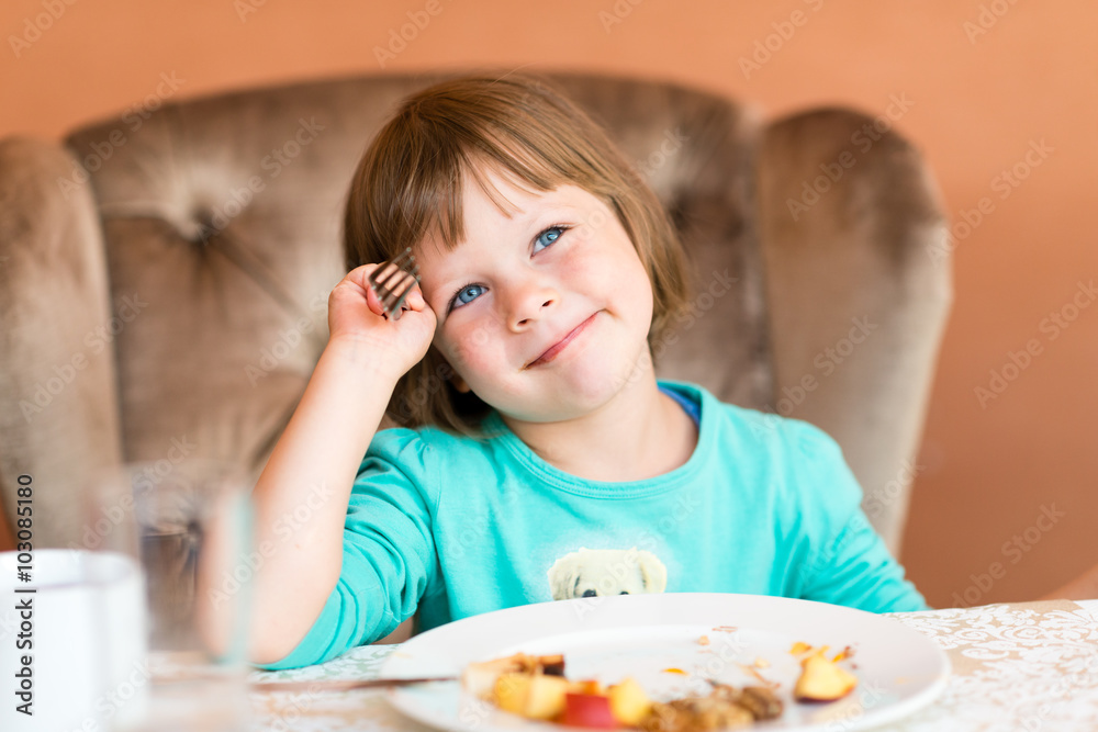 Adorable little girl eating pancake and fruits Adorable little girl eating pancake and fruits